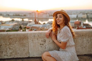 Gün batımında şehir merkezine bakan genç bir bayan turist. Seyahat ve turizm kavramı.