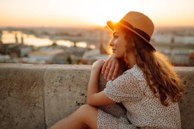 Gün batımında şehir merkezine bakan genç bir bayan turist. Seyahat ve turizm kavramı.