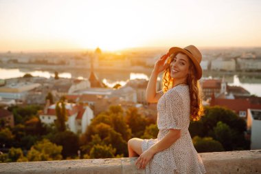 Gün batımında şehir merkezine bakan genç bir bayan turist. Seyahat ve turizm kavramı.