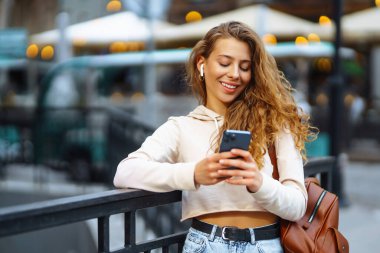 Akıllı telefon kullanan bir kadının fotoğrafı. Sokakta mesajlaşan güzel bir kadın. Güzel bir kadın şehirde vakit geçiriyor.. 