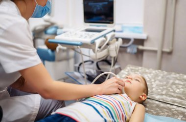 Doktor, klinikte modern tıbbi gereçler kullanan küçük bir çocuğun kalp ve abdominal organlarını ultrason muayenesi yapıyor. Pediatri ve çocuk gelişimi izleme.