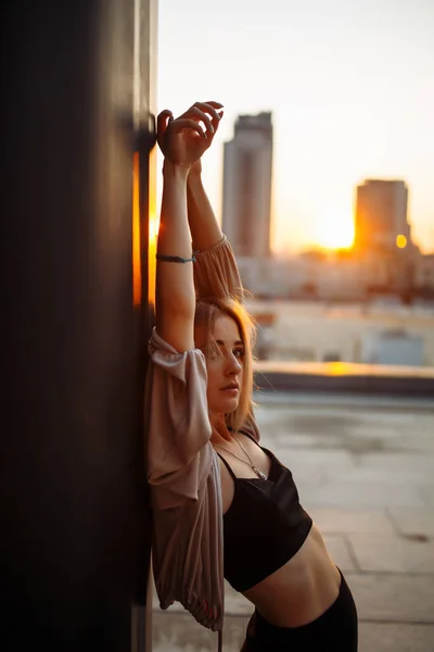 照片拍摄在屋顶上 日落时年轻女子躺在房顶上 时尚观念 — 图库照片