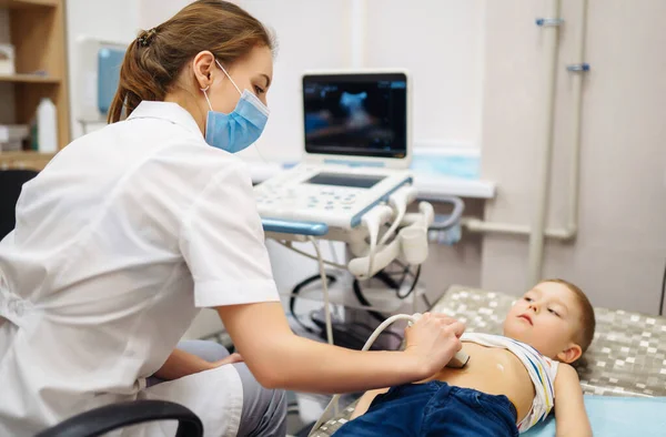 医師は 診療所で現代の医療機器を使用して 小さな男の子の心臓や腹部器官の超音波検査を行います 小児科と小児発達モニタリング — ストック写真