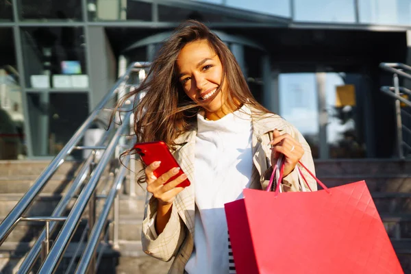 ショッピングバッグや携帯電話を持ってモールの近くに立つ若い女性 黒の金曜日 — ストック写真