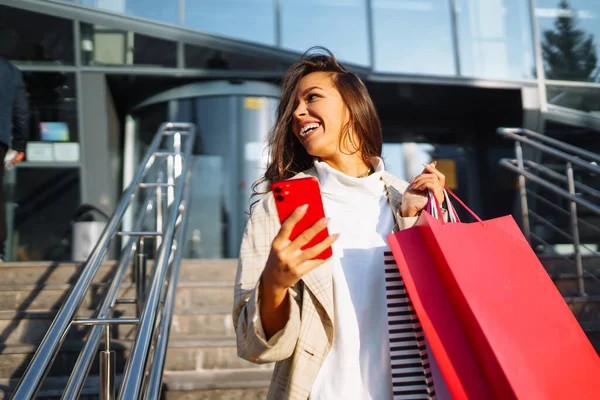 Jonge Vrouw Buurt Van Winkelcentrum Met Boodschappentassen Een Mobiele Telefoon — Stockfoto