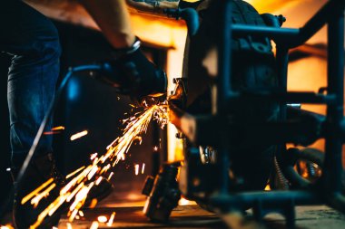 Kıvılcımla kaynak yaptıktan sonra motosiklet tamiri. Garajda motosiklet tamir eden genç adam.. 