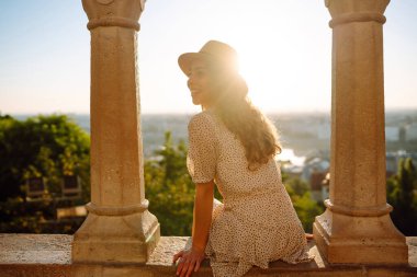 Genç bayan turist gün batımında şehir manzarasının tadını çıkarıyor. Seyahat ve turizm kavramı.