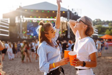 Müzik festivalinde bira içen iki genç kadın. Plaj partisi, yaz tatili