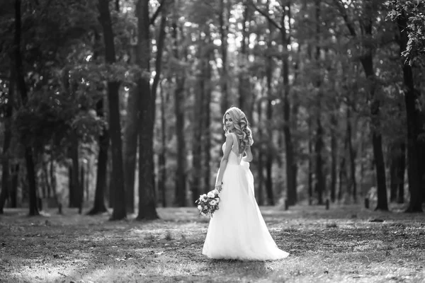 Black and white photo of Beautiful bride in a white dress for a walk in the park. Wedding day. Marriage. Fashion bride.