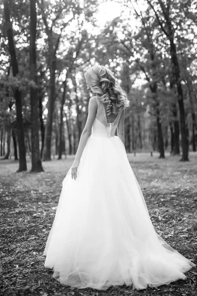 穿着白衣的漂亮新娘在公园散步的黑白照片 婚礼当天 时尚新娘 — 图库照片