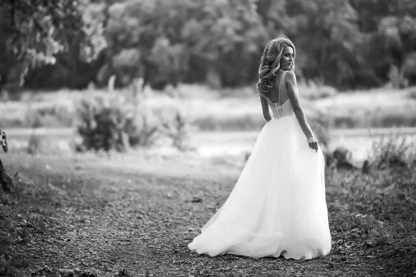 穿着白衣的漂亮新娘在公园散步的黑白照片 婚礼当天 时尚新娘 — 图库照片