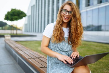 Dışarıda dizüstü bilgisayarı olan genç bir kadın. Eğitim çevrimiçi. Bağımsız, İş, Alışveriş, Blogculuk.