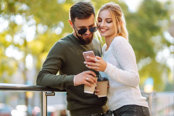 朝の街を歩いている間に楽しい会話 コーヒーを飲み 電話を使用している若いカップル リラクゼーション ライフスタイル 自撮り ブログ — ストック写真