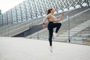 Spor giyim sektöründe spor yapan kadın dışarıda egzersiz yapıyor. Genç bir kadın esneme egzersizi yapıyor. Spor, aktif yaşam tarzı, sağlıklı yaşam tarzı konsepti.