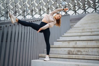 Spor giyim sektöründe spor yapan kadın dışarıda egzersiz yapıyor. Genç bir kadın esneme egzersizi yapıyor. Spor, aktif yaşam tarzı, sağlıklı yaşam tarzı konsepti.