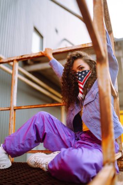 Amerikan bandanalı şık kıyafetler içinde sokakta havalı bir dansçı. Genç dansçı kadın birkaç hareket gösteriyor. Spor, dans ve şehir kültürü konsepti.