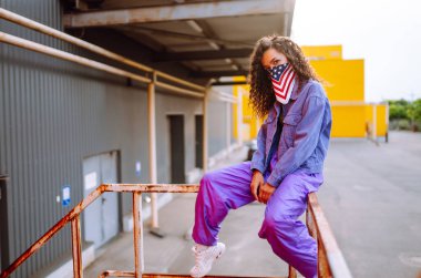 Amerikan bandanalı şık kıyafetler içinde sokakta havalı bir dansçı. Genç dansçı kadın birkaç hareket gösteriyor. Spor, dans ve şehir kültürü konsepti.