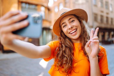 Cep telefonu tutan mutlu kadın akıllı telefon kamerasıyla selfie çekiyor. Bir turist caddelerde yürüyor ve şehrin mimarisinden zevk alıyor, manzaranın resimlerini çekiyor. Selfie zamanı.. 