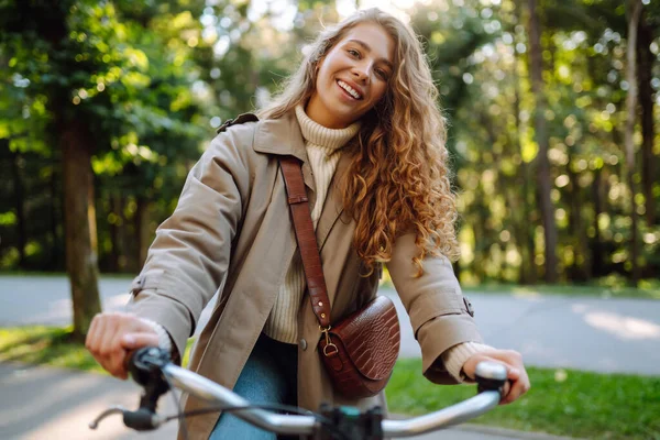 Smiling Woman Curly Hair Coat Rides Bicycle Sunny Park Potret — Stok Foto