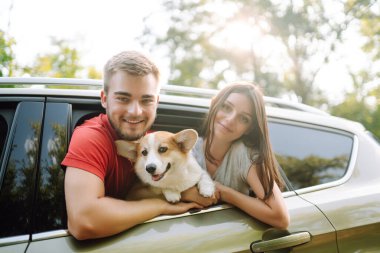 Köpekli sevimli genç bir çift arabanın arka koltuğunda oturuyor. Bir kadınla ve sevgili köpeğiyle seyahat eden mutlu bir adam. Aktif yaşam tarzı kavramı, seyahat, hafta sonu, rahatlama.