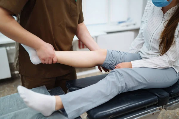 Patient visits a doctor after suffering a leg injury. The doctor examines the patient, examines the picture of the patient. Osteopathy, chiropractic, leg correction, rehabilitation.