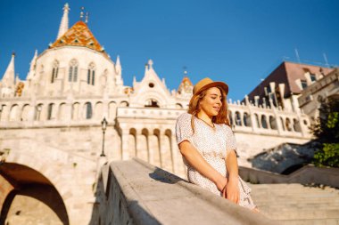 Şafak vakti şapkalı mutlu genç kadın güzel binaların manzarasının tadını çıkarıyor. Yaşam tarzı, eğlence, turizm konsepti.