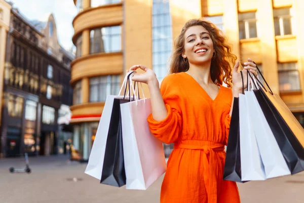 여자가 양지바른 거리를 걸어가고 쇼핑하는 여자는 날씨를 즐긴다 할인의 — 스톡 사진