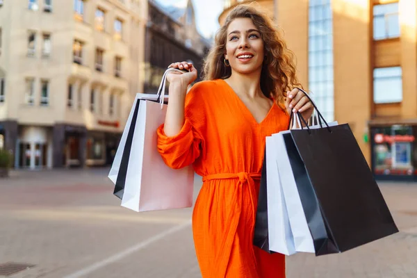 여자가 양지바른 거리를 걸어가고 쇼핑하는 여자는 날씨를 즐긴다 할인의 — 스톡 사진