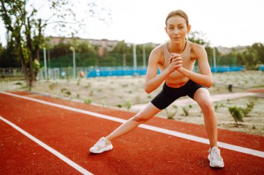 Sporcu kadın sabahları dışarıda egzersiz yapıyor. Spor alanında egzersiz yapan enerjik bir kadın. Sağlıklı yaşam tarzı kavramı. Spor, antrenman..