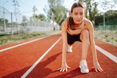 Sporcu kadın sabahları dışarıda egzersiz yapıyor. Spor alanında egzersiz yapan enerjik bir kadın. Sağlıklı yaşam tarzı kavramı. Spor, antrenman..