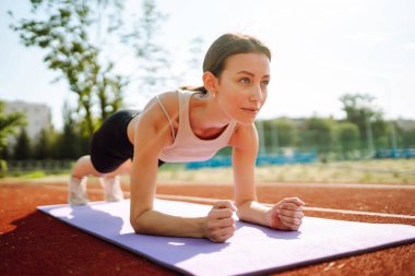Sporcu kadın sabahları dışarıda egzersiz yapıyor. Spor alanında egzersiz yapan enerjik bir kadın. Sağlıklı yaşam tarzı kavramı. Spor, antrenman..