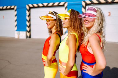  Renkli mayo giymiş gülümseyen dansçılar sahilde dans ediyorlar. Sabahleyin üç kadın spor için içeri giriyor. Spor, spor, aerobik dışında. Aktif spor.