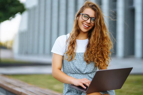 Mujer Joven Sonriente Gafas Con Auriculares Inalámbricos Una Computadora Portátil —  Fotos de Stock