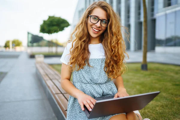 Mujer Joven Sonriente Gafas Con Auriculares Inalámbricos Una Computadora Portátil —  Fotos de Stock