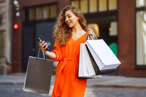 晴れたヨーロッパの街を歩いている間にスマートフォンを使って買い物をする幸せな女性観光客 ショッピングライフスタイルの概念 消費主義 — ストック写真