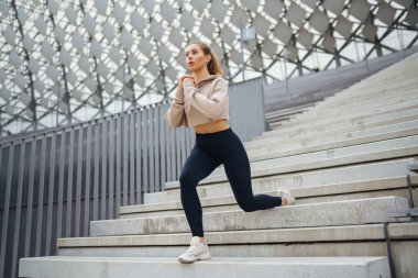 Aktif yaşam tarzı. Genç fitness kadını dışarıda egzersiz yapıyor ve esniyor. Formda bir kadın sağlığını sporla korur. Spor, spor eğitimi..