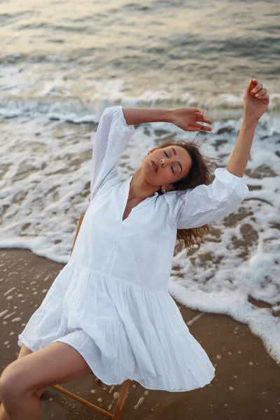 海滨漂亮的模特儿穿着漂亮的白色连衣裙摆姿势 一位年轻女子在海滩上享受着令人难以置信的日出 生活方式 旅行概念 — 图库照片