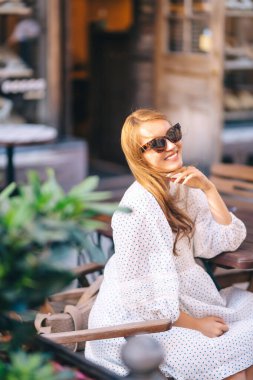 Şehir caddesinde bir kafede oturan güzel bir kadın. İnsanlar, moda, yaşam tarzı, seyahat ve tatil kavramı