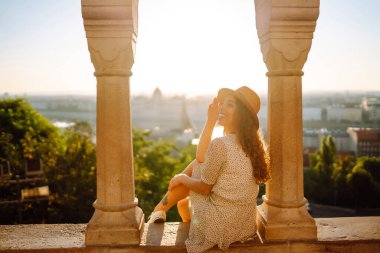 Young female tourist looking at panoramic view of the city at sunset.  Lifestyle, travel, tourism, nature, active life.