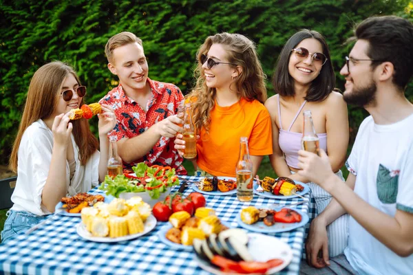 Bir grup genç arkadaş piknik için bahçede toplandı. Arkadaşlar eğlenir, doğayla iletişim kurar, bira içerler. Bölük barbekü için toplandı. Tatil kavramı, yaşam tarzı, tatil.