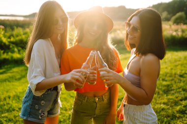 Piknikte bira içen üç kadın, şerefe. Tatil, piknik, arkadaşlık veya bayram konsepti.