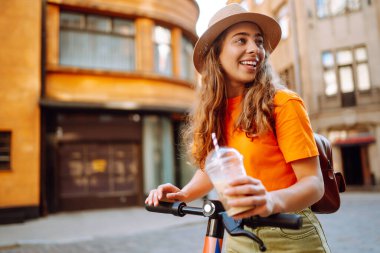 Şehirde elektrikli scooter kullanan genç bir kadın. Aktif hayat. Ekolojik ulaşım kavramı.