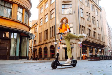 Şehirde elektrikli scooter kullanan genç bir kadın. Aktif hayat. Ekolojik ulaşım kavramı.