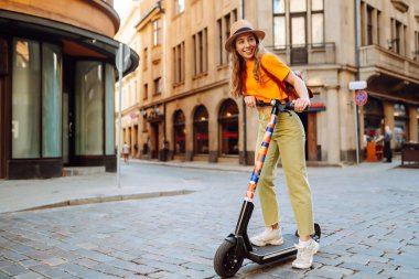 Şehirde elektrikli scooter kullanan genç bir kadın. Aktif hayat. Ekolojik ulaşım kavramı.