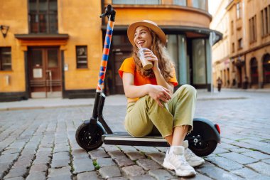 Şehirde elektrikli scooter kullanan genç bir kadın. Aktif hayat. Ekolojik ulaşım kavramı.