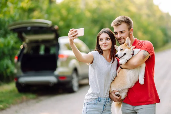 stock image Selfie time. Young couple together with their beloved pet on a walk doing selfie.The concept of an active lifestyle, travel, love and vacation. Pet and human.