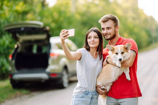 stock image Selfie time. Young couple together with their beloved pet on a walk doing selfie.The concept of an active lifestyle, travel, love and vacation. Pet and human.