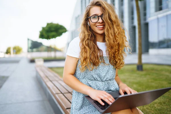 Lachende Vrouwelijke Freelancer Zit Straat Met Laptop Draadloze Koptelefoon Oproepen — Stockfoto