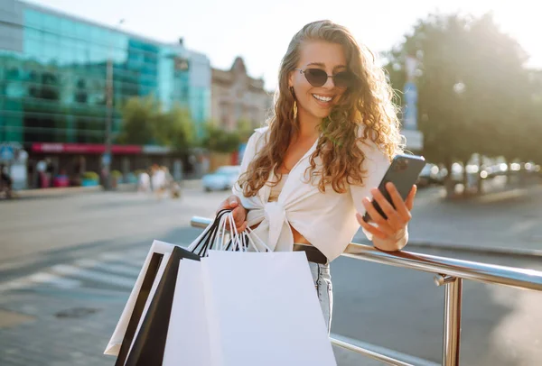 快乐的女人 带着购物袋走在阳光灿烂的街上 生活方式 消费主义的概念 — 图库照片