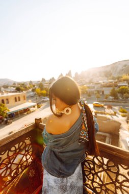 Genç bir kadın, Cappadocia 'da çarpıcı şehir manzaralı bir terasta meditasyon yapıyor. Aktif yaşam tarzı, tatil, dinlenme.